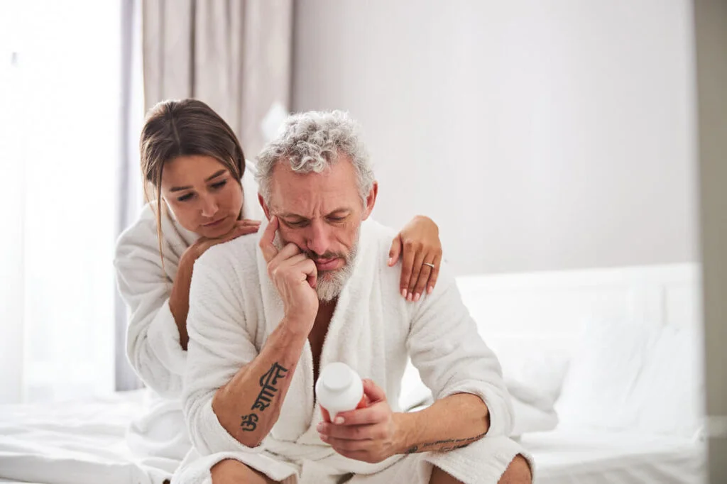 a man who has a problem with erectile dysfunction is holding a bottle of Lisinopril