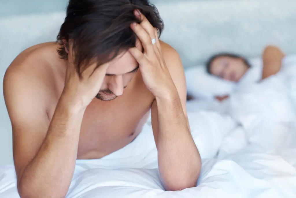 a man with erectile dysfunction holding his head and is problematic after not satisfying her partner